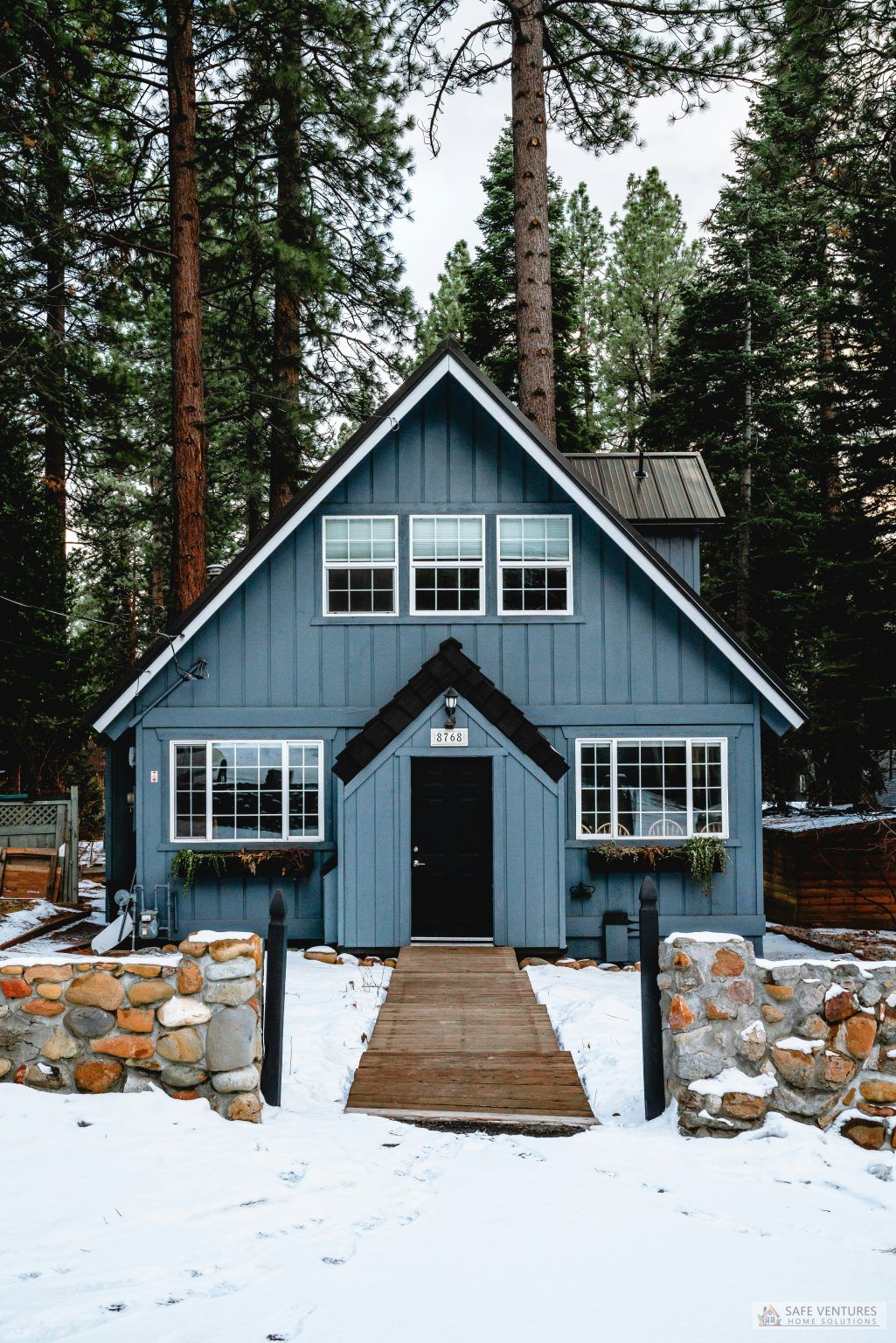 blue house in winter with snow in the yard